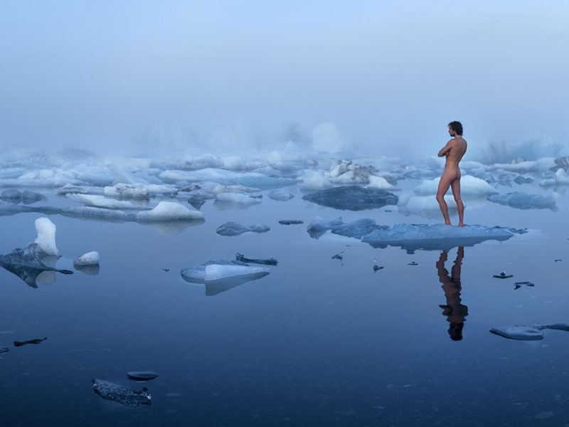 Un des clichés de l'exposition Faire partie, de Gaspard Noël, un homme nu se tient, de dos, sur un morceau de glace dérivant sur l'eau